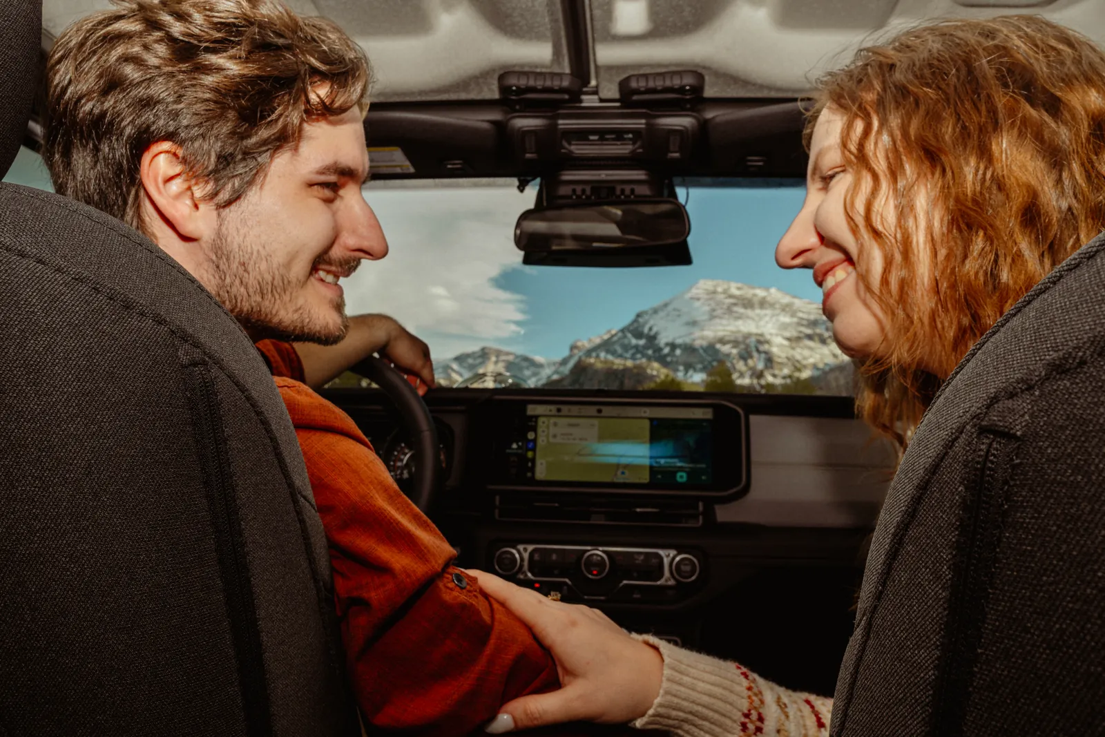 Couple laughing inside a Jeep with mountains out the window, engagement session in Rocky Mountain National Park