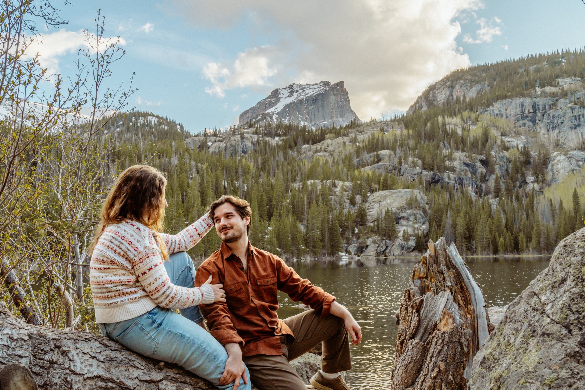 Close-up of an engaged couple kissing in front of a snow-capped peak, Rocky Mountain National Park