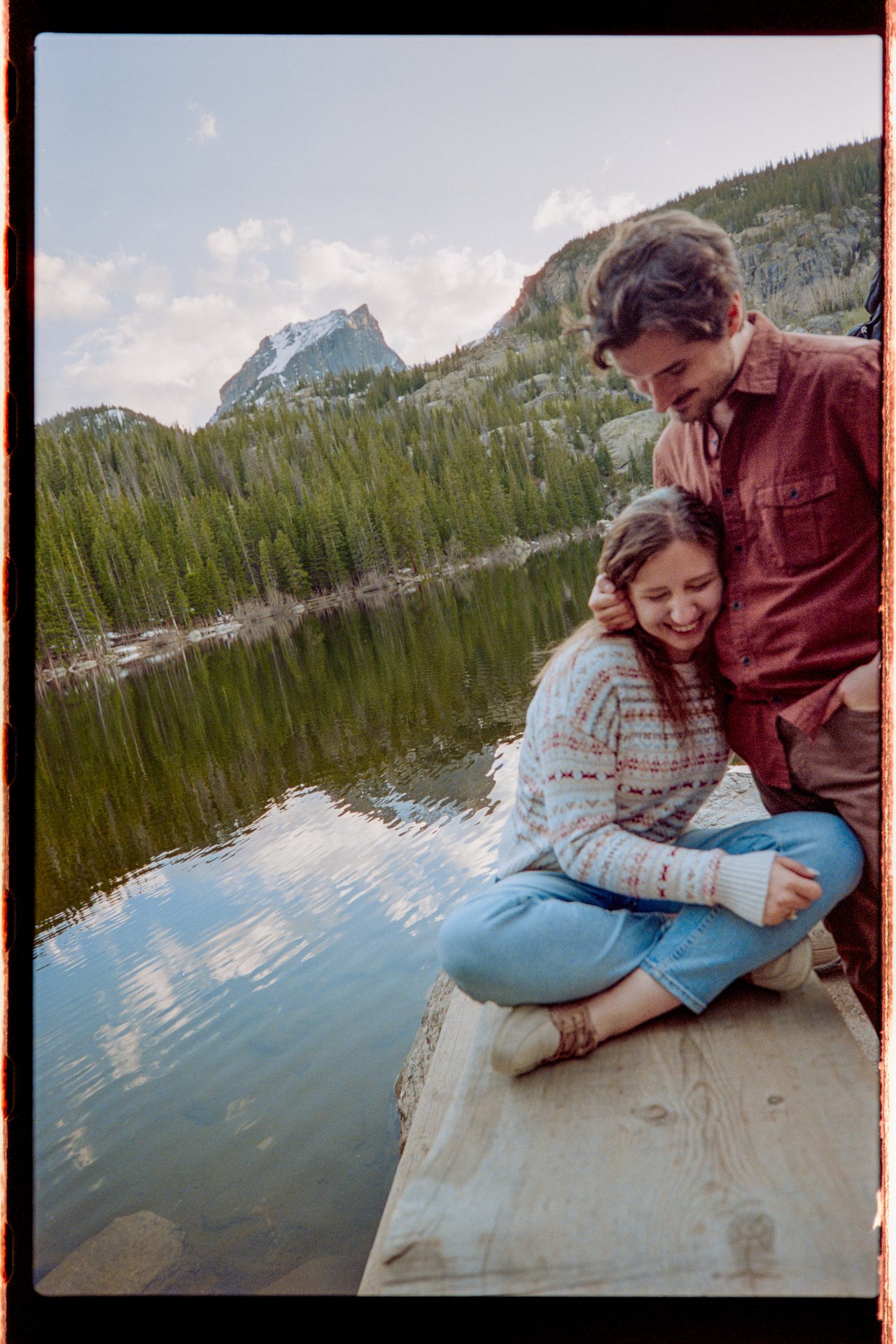 Engaged couple laughing lakeside, 35mm film photo, Rocky Mountain National Park