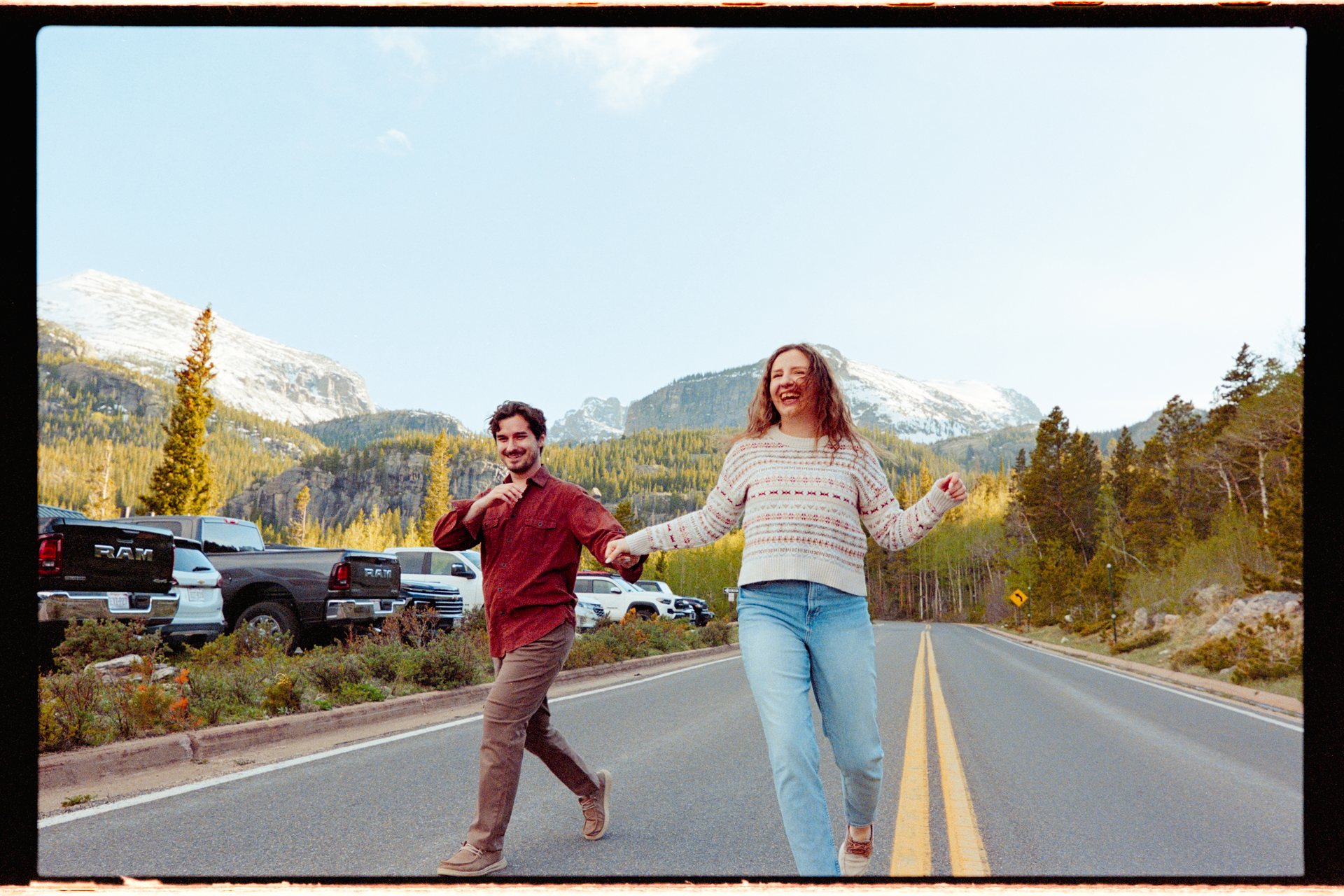 Engaged couple dancing across a park road, 35mm film photo, Rocky Mountain National Park