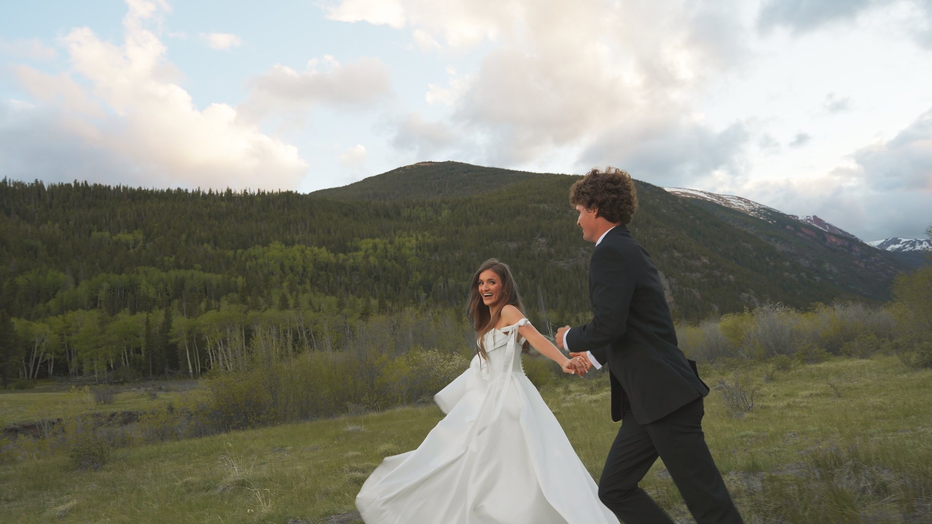 Couple running through a meadow, still from a Motus wedding film, Rocky Mountain National Park